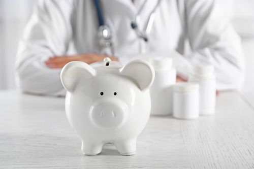 © Africa Studio - stock.adobe.com Foto: Arzt sitz hinter Sparschwein