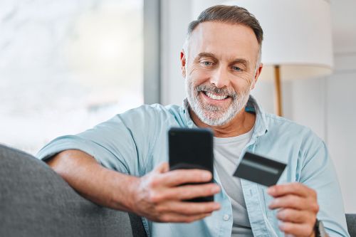 © K Davis/peopleimages.com - stock.adobe.com Foto: Mann mit Smartphone und Kredikarte